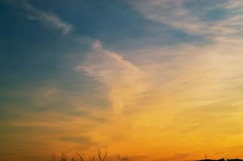 Vibrant sunset sky with wispy clouds transitioning from deep blue to warm o.. Stock Photos