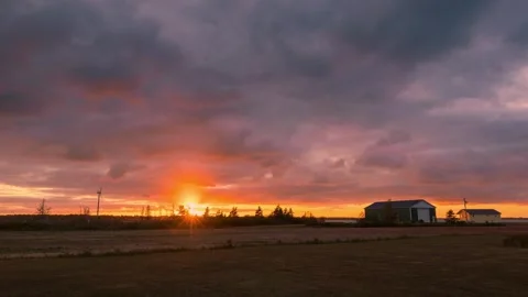 Vibrant sunset time lapse over a farm with wind turbines in the background. Stock Footage 317786462