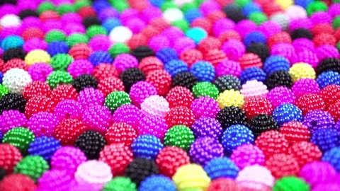 Vibrant textured beads moving across frame showing various bright colors for Stock Footage 340952878