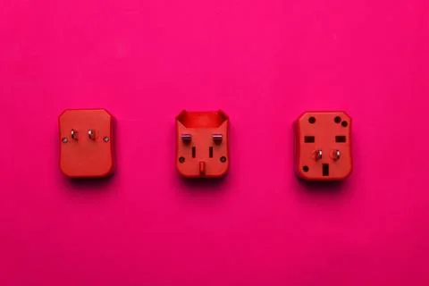 Vibrant three red electric multi plug for travel on pink background Stock Photos