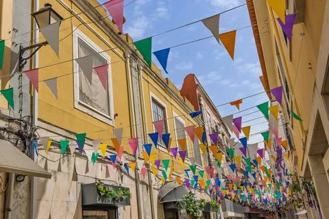 Vibrant triangular bunting flags in multiple colors are strung across a sunny Stock Photos