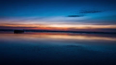 Vibrant twilight sky reflecting on wet beach sand at ocean shoreline wide shot Stock Footage 342396091