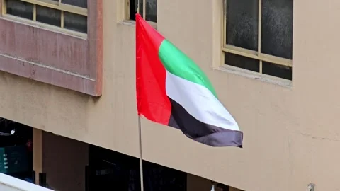 A vibrant UAE flag proudly waves against a building, showcasing national Video stock 311765839