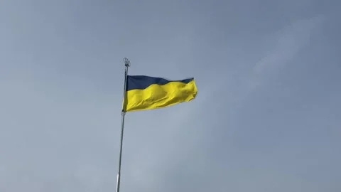 A vibrant Ukrainian flag flutters in the wind atop a building against a sky. Vídeos de archivo 330543083