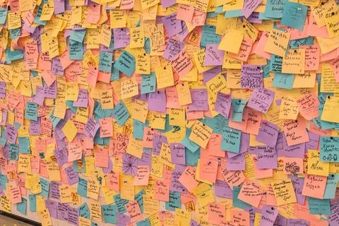 Vibrant wall with densely packed sticky notes, text in various colors, remi.. Stockfoto's