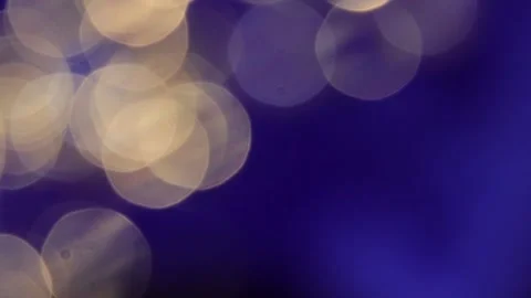 Vibrant white and gold two-tone bokeh video on the left against a blue backgroun Stock Footage 317533608