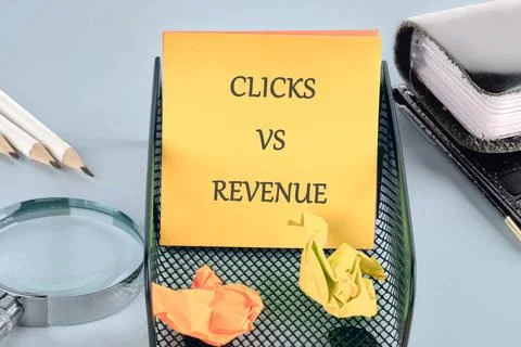A vibrant workspace displays a notepad with the words clicks vs revenue, surr Stock Photos
