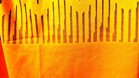 Vibrant yellow fabric featuring a repeating pattern of dark vertical lines Stock Photos