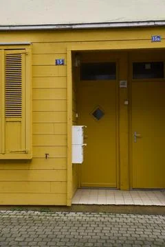 This vibrant yellow facade features a unique entryway and decorative shutte.. Stock Photos