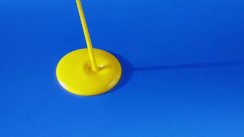 Vibrant Yellow Paint Dripping Gracefully on a Blue Surface An Artistic and Fluid Stock Footage 306587183
