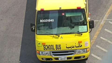 A vibrant yellow school bus, possibly in the Middle East, travels Stock Footage 311885620