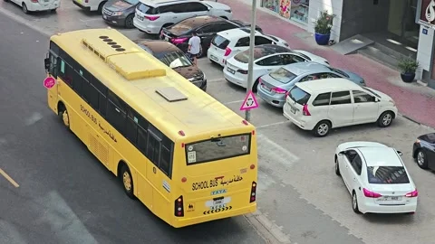 A vibrant yellow school bus is stopped on the roadside as a student Stock Footage 311885050