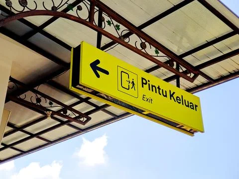 A vibrant yellow sign indicates an exit with an arrow and pictogram under a.. Stock Photos