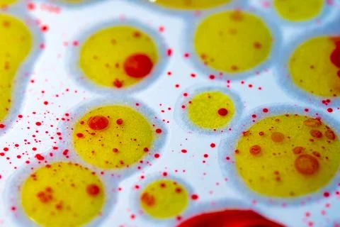 Vibrant yellow spheres float in white, dotted with red specks Stock Photos