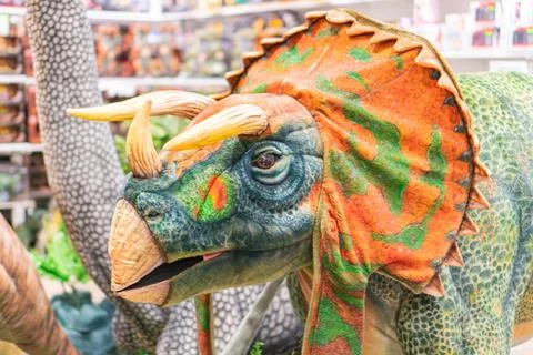 A vibrantly colored, large dinosaur model stands out against a blurred ware.. Stock Photos