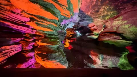 Vibrantly Lit Cave with Reflections of Multicolored Lights on Stone Walls Stock Photos