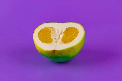 A Vibrantly Styled Cut Citrus Fruit Against a Purple Background Representing Stock Photos