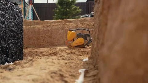 Vibrating compactor preparing sand for a building foundation Stock Photos