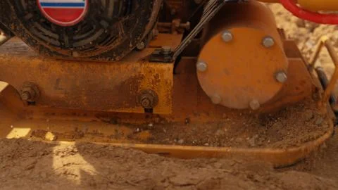 Vibrating plate compactor consolidating soil at construction site Stock Photos