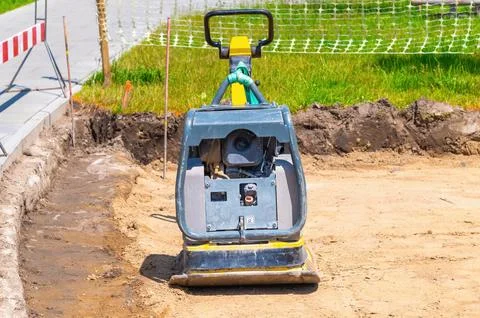 Vibrating plate compactor machine at a road construction site. Soil compact.. Stock Photos