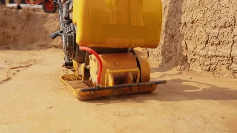 Vibratory plate compactor compacting sand at a construction site Stock Footage 341294824
