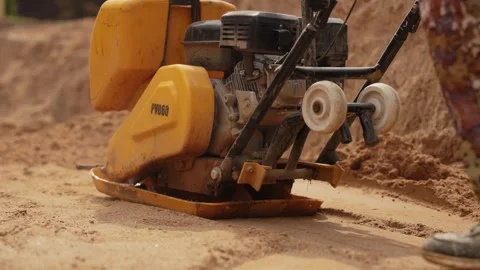 Vibratory plate compactor compacting sand at a construction site Stock Footage 341294844