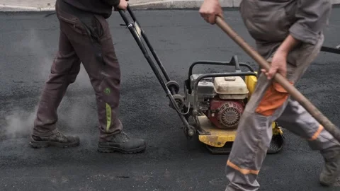 Vibratory plate compactor machine compacting fresh black asphalt on road Vidéo 339802397