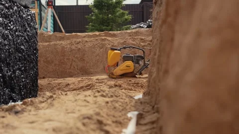 Vibratory plate compactor tamping sand at construction site Stock Footage 341294850