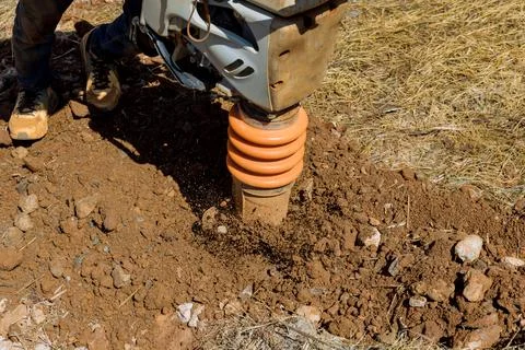 A vibratory plate on a tamping machine compactor tool jumps into the air as it Stock Photos