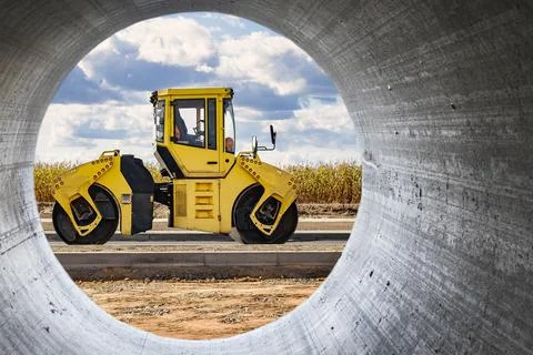 Vibratory road roller lays asphalt on a new road under construction. Close-up Stock Photos