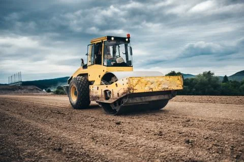Vibratory soil compactor working on highway construction site Stock Photos