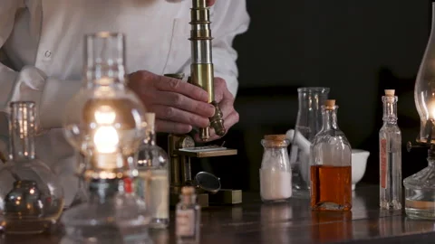 Victorian scientist looking through a brass microscope Stock Footage 344697833