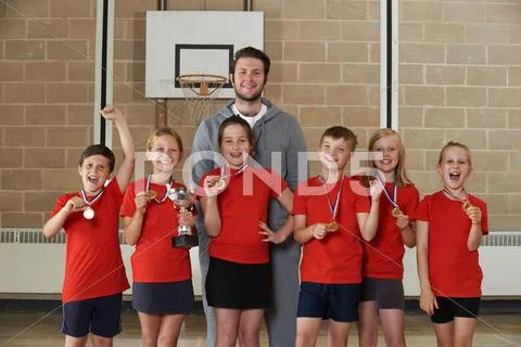 Victorious School Sports Team With Medals And Trophy In Gym
