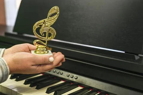 Victory trophy in shape of treble clef held by woman, celebrating festival .. Stock Photos