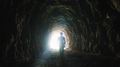 Video 4K of a man walking in an ancient tunnel to the light Video stock 167690989