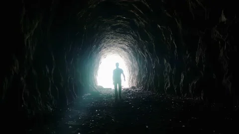 Video 4K of a man walking in an ancient tunnel to the light Stock Footage 167690998