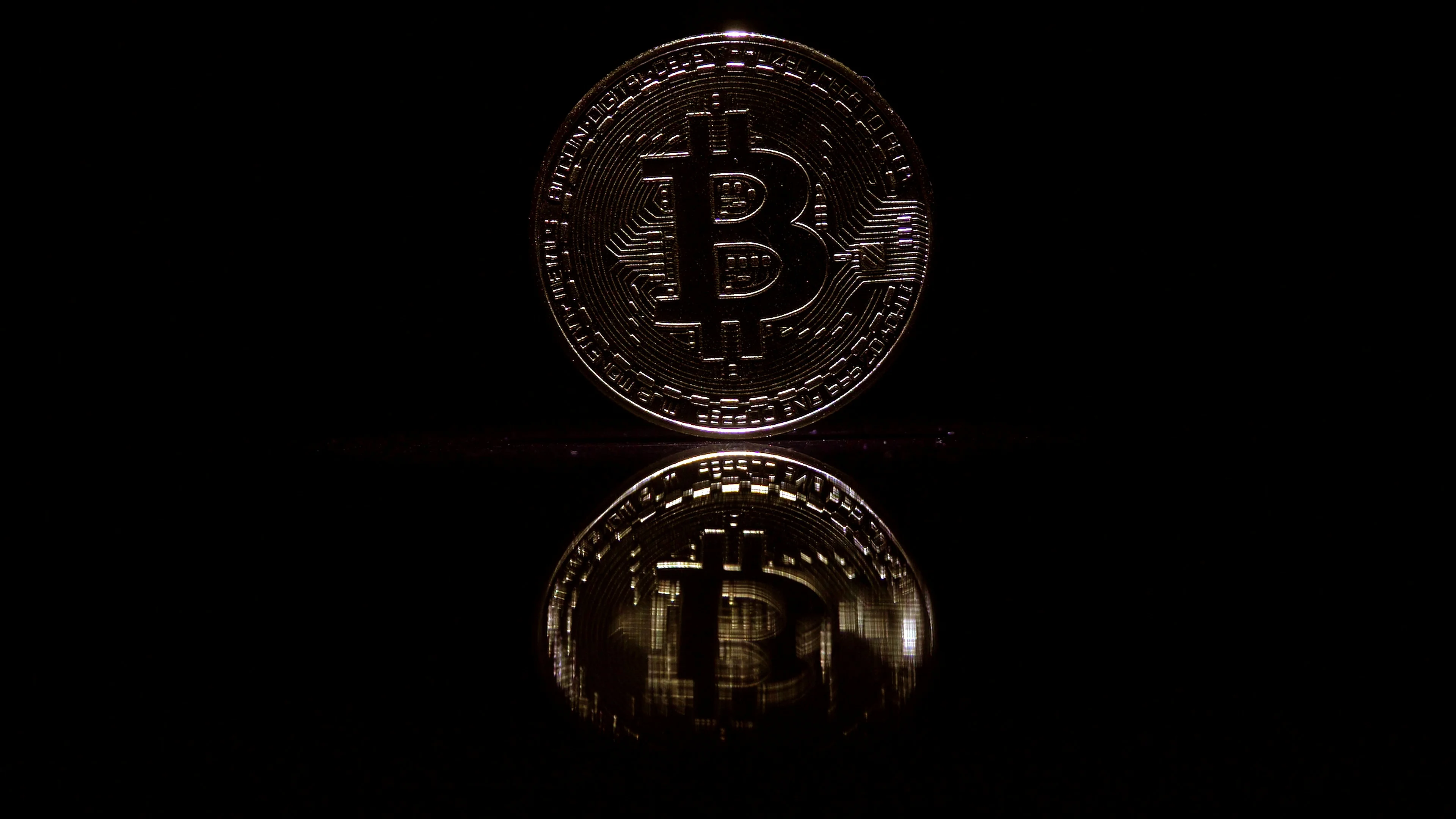 Video in 4k resolution bitcoin coin on a black background. Playing with light