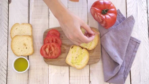 Video 4k of a woman's hands preparing a toast with olive oil, ham and tomato. Stock Footage 133368776