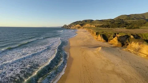 This video is about 4k Drone flying over sand beach &amp; pacific ocean Stock Footage 73244839