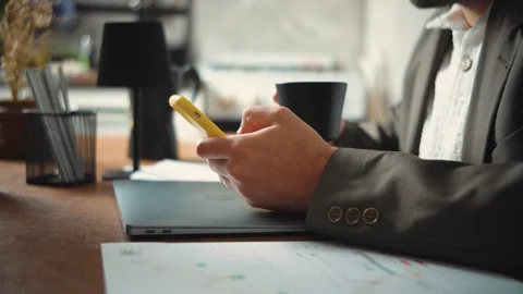 Video of an anonymous businessman using his smartphone and drinking coffee durin Stock Footage 346329861