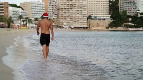 Video from the back of a bearded man with a Santa Claus hat walking on the sh Video stock 140940947