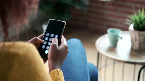 Video of back of young woman using her mobile phone while sitting on sofa at  Stock Footage 168567555