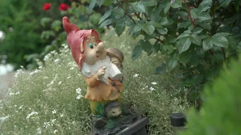 Video for the background sculpture of a gnome with a hedgehog in a green garden Video stock 157591953
