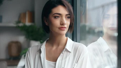 Video of beautiful woman posing while standing next to the window at home Stock Footage 313357563