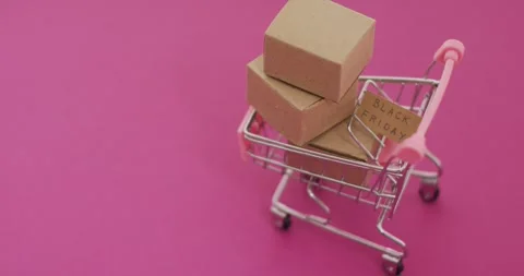 Video of black friday text on cardboard and boxes in shopping trolley on pink Stock Footage 331294519