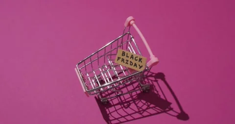 Video of black friday text on cardboard in shopping trolley on pink background Stock Footage 331294521