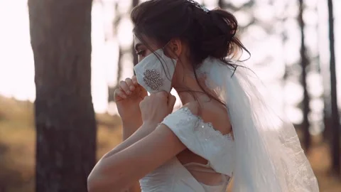 A video of a bride in the park. She puts on her mask with both hands. Stock Footage 131766519