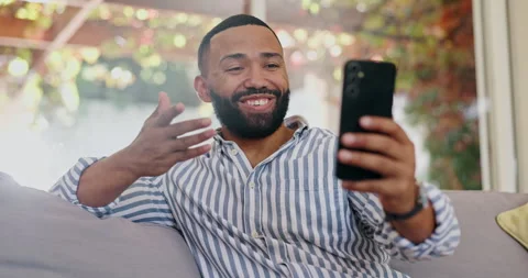 Video call, sofa and black man with conversation in a living room with smile and Stock Footage 306440256