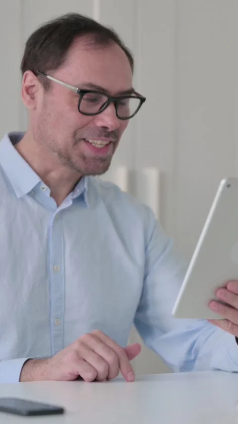 Video Call on Tablet by Middle Aged Man in Office, Vertical Video 스톡 동영상 339585092