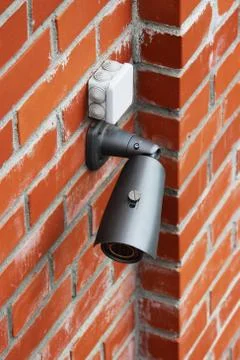 A video camera on a red brick wall protects the territory from the invasion Stock Photos